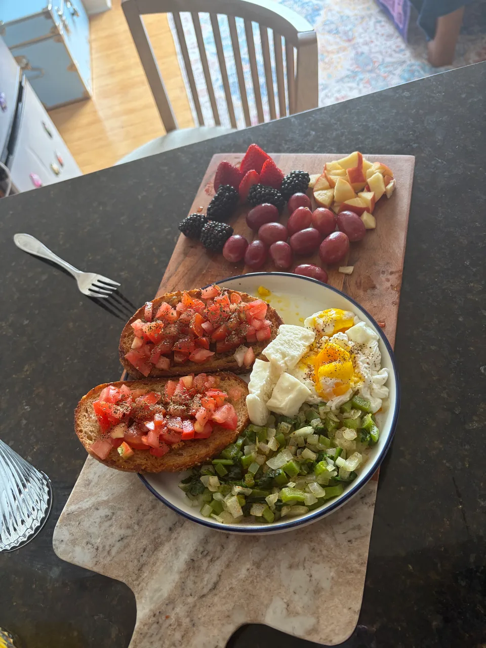 A homemade meal with tomato toast, eggs, vegetables and fresh fruit